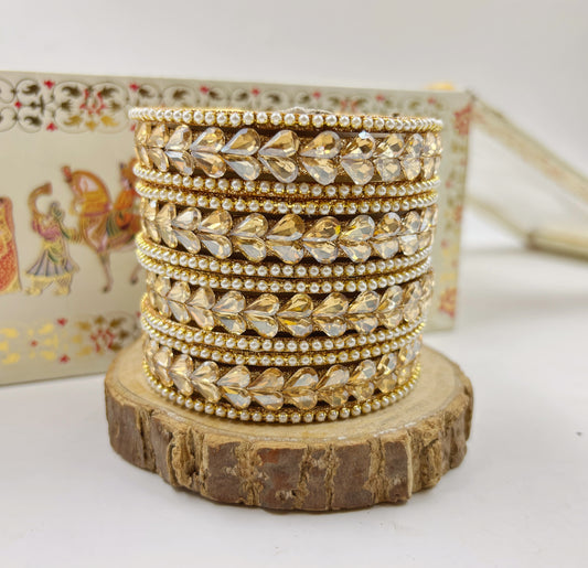 Stack of gold and silver bangles on a wooden stand with a decorative background by hitesh bangles