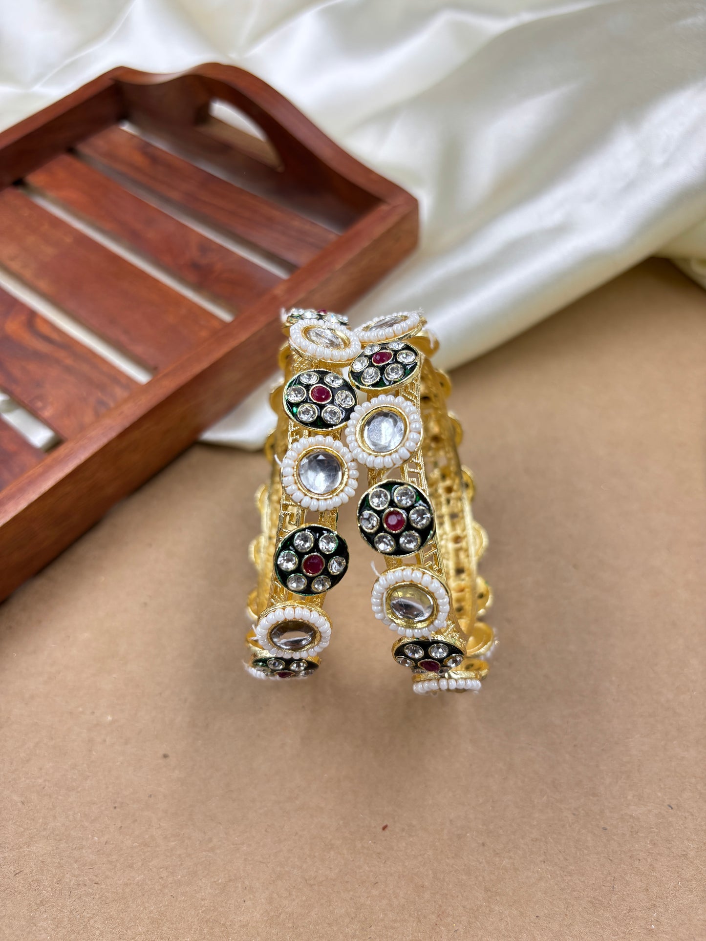 Gold and black jewelry set on a wooden surface by hitesh bangles