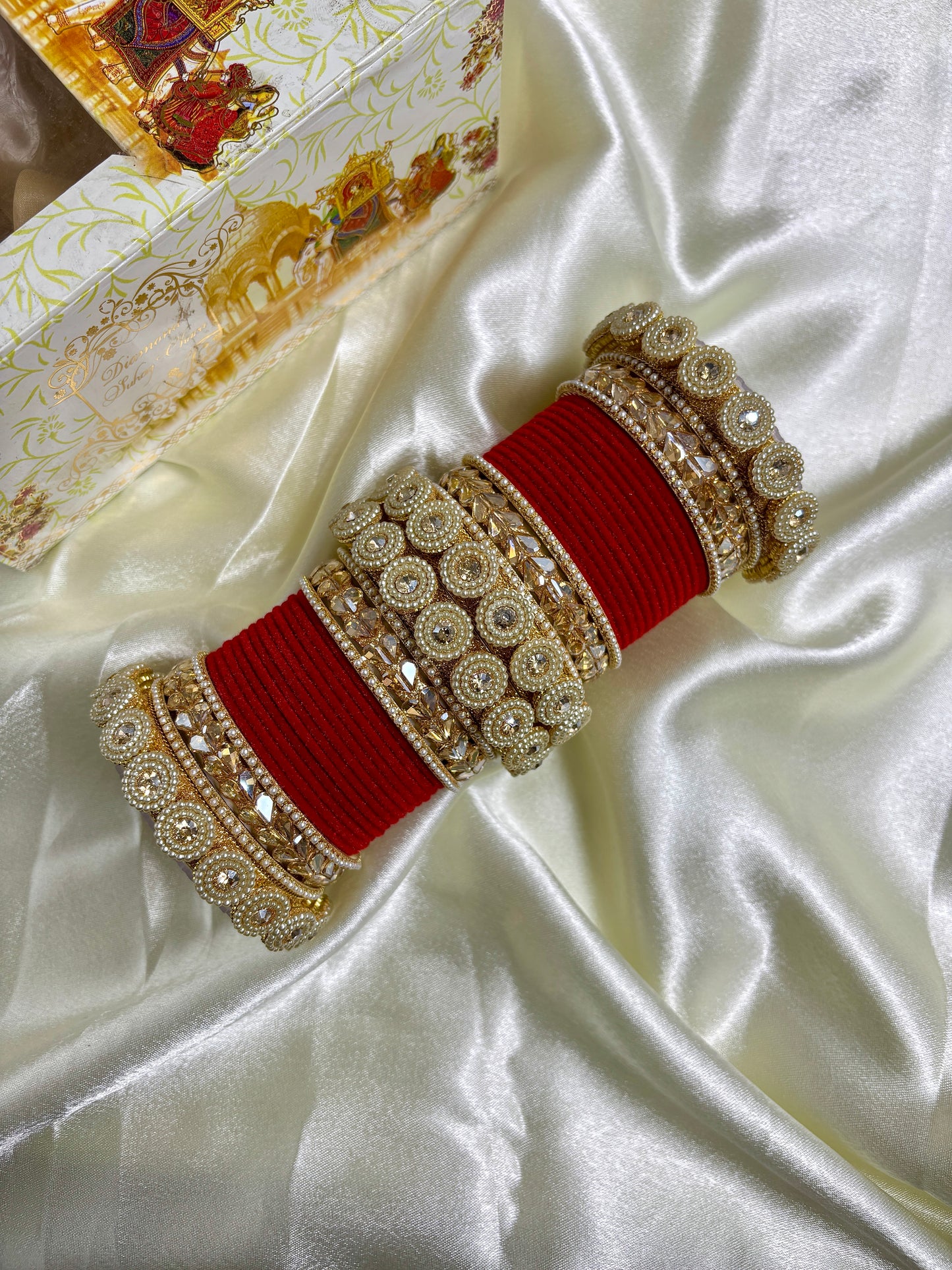 Decorative red and gold belt on a satin surface by hitesh bangles