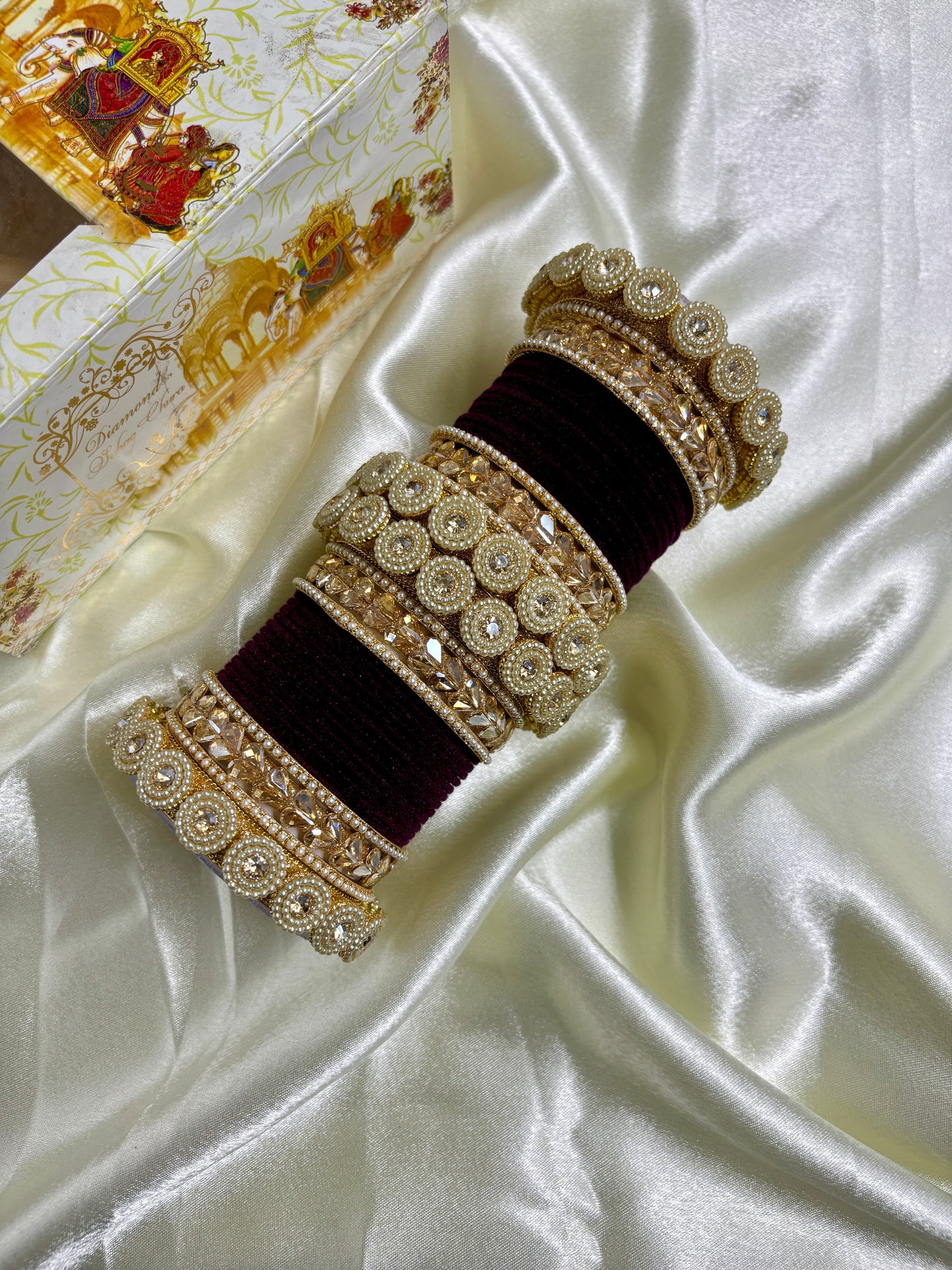 Decorative phone case with gold embellishments on a white satin background by hitesh bangles