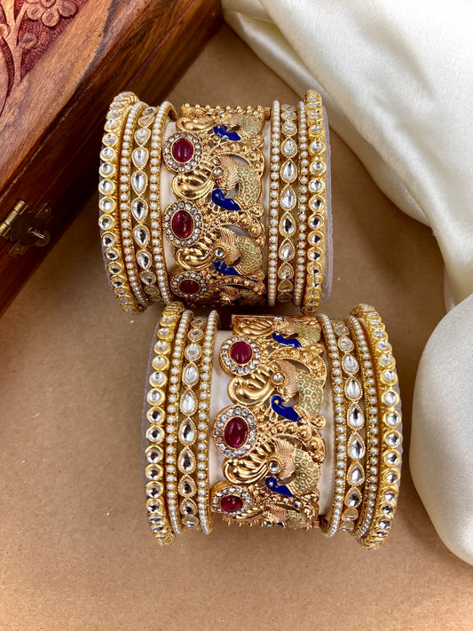 Decorative gold bangles with gemstones on a beige surface by hitesh bangles