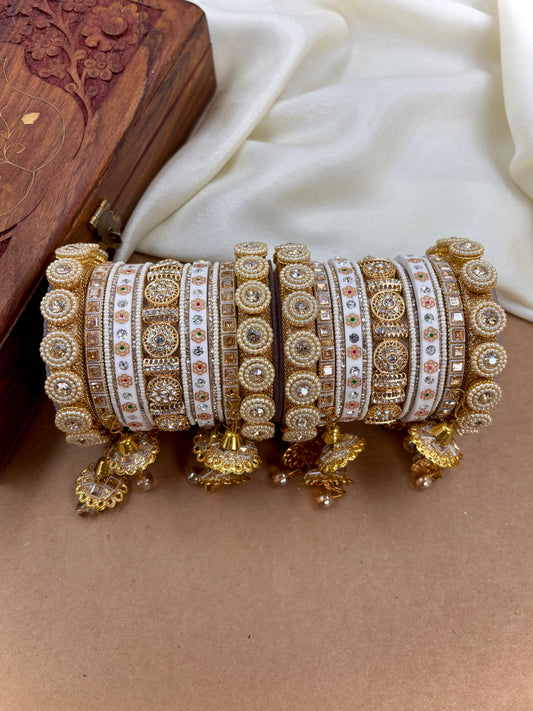 Set of ornate gold bangles with intricate designs on a beige surface by hitesh bangles