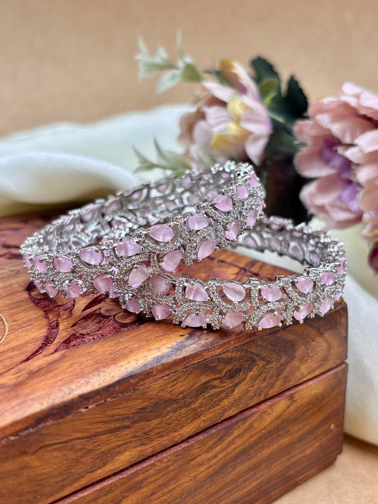 Silver and pink beaded bracelet on a wooden surface with flowers in the background by hitesh bangles