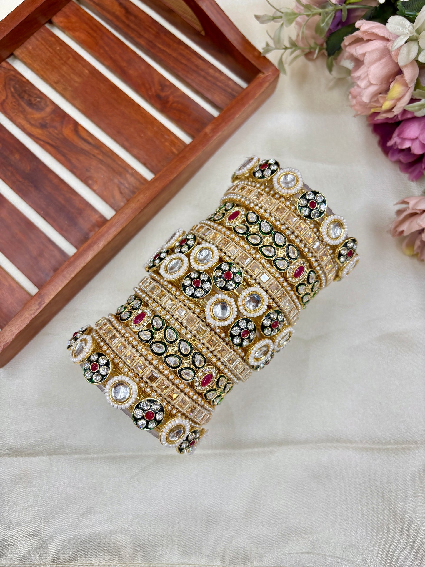 Decorative bangles with intricate designs on a white fabric background by hitesh bangles