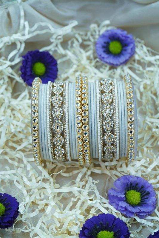 Decorative bangles with intricate designs on a textured surface with purple flowers by hitesh bangles