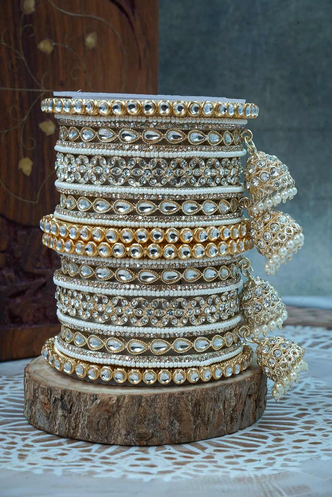 Stack of gold and silver bangles on a wooden block with a neutral background by hitesh bangles