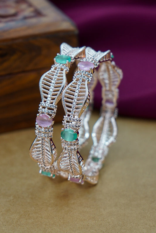 Pair of silver bangles with gemstones on a textured surface by hitesh bangles