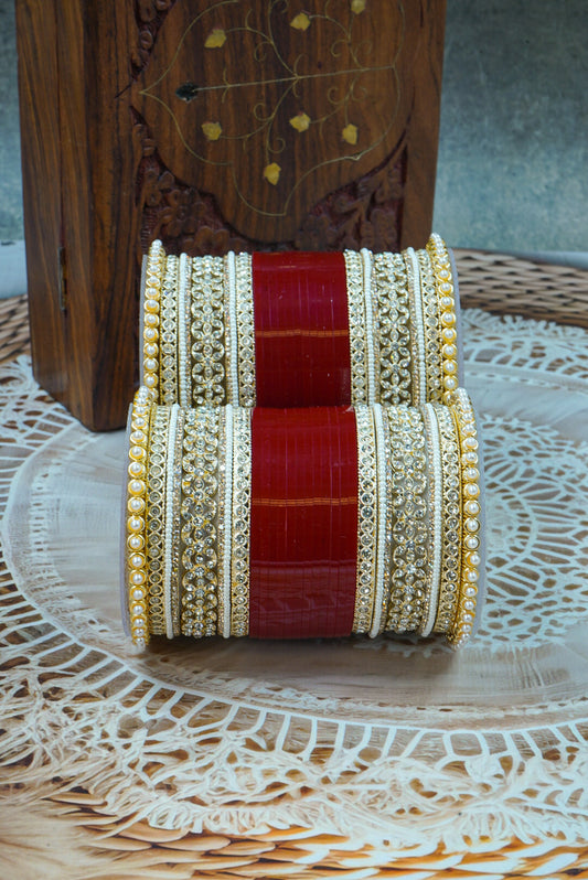 Decorative bangles with red and gold patterns on a wooden surface by hitesh bangles