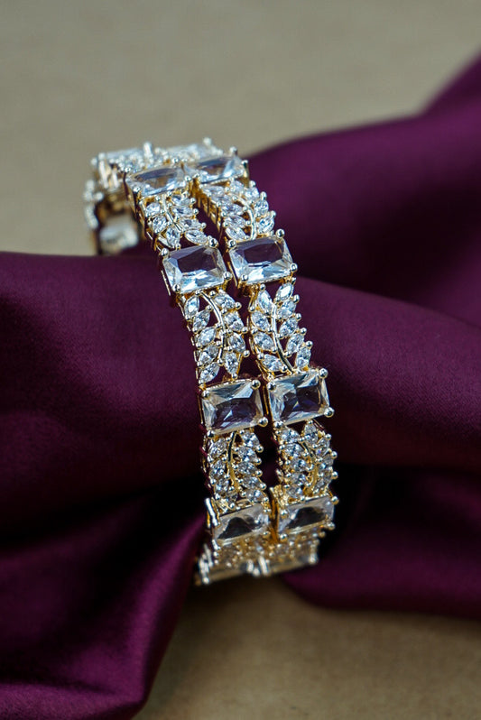 Gold bracelet with clear stones on a purple fabric background by hitesh bangles