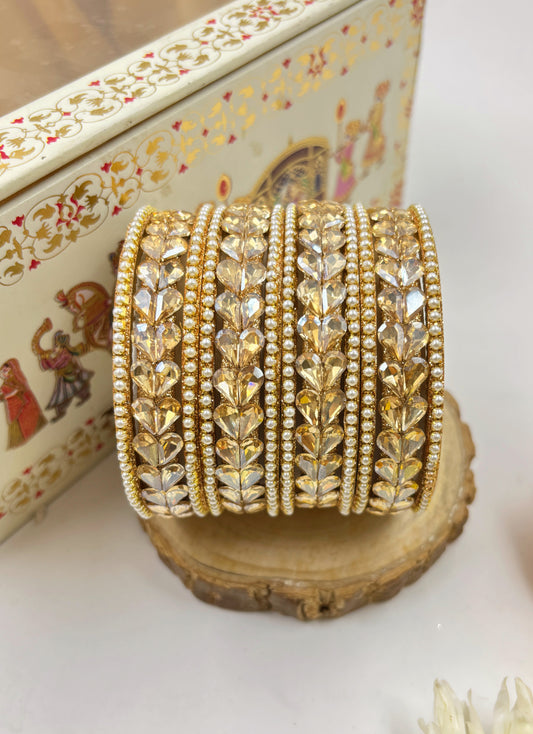 Set of gold bangles on a decorative stand with a patterned box in the background by hitesh bangles
