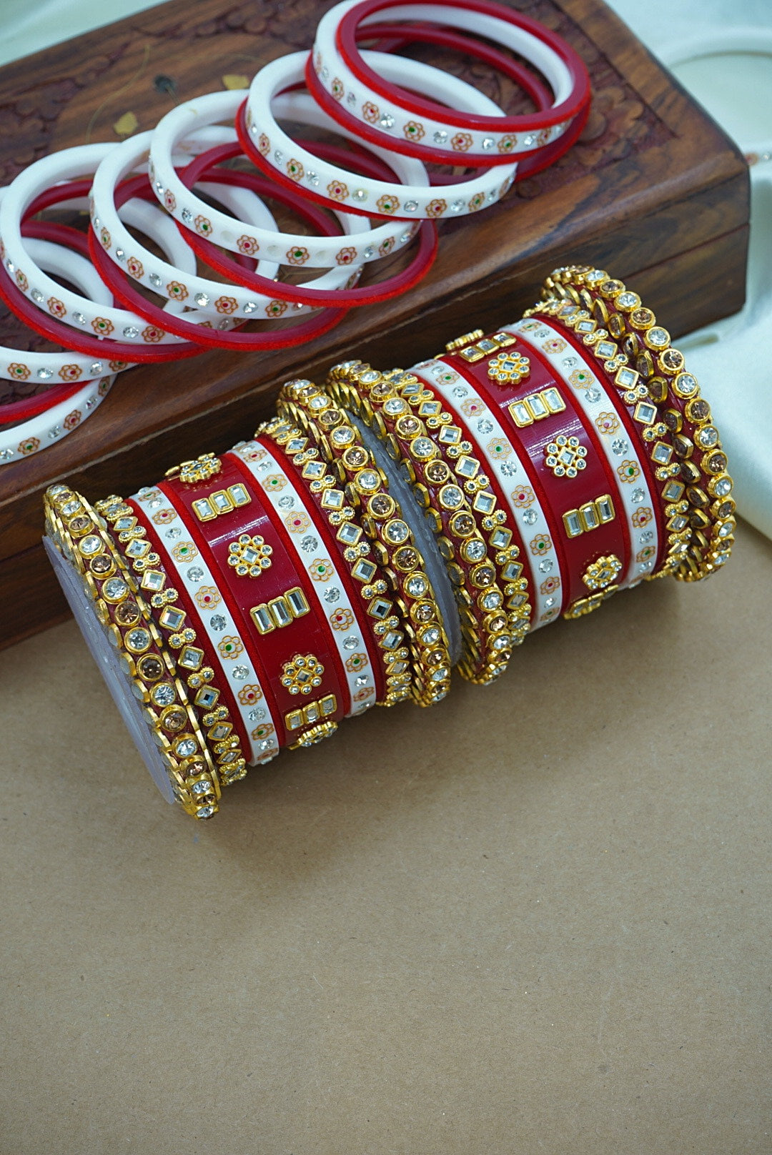 Decorative bangles with gold and red patterns on a wooden surface by hitesh bangles