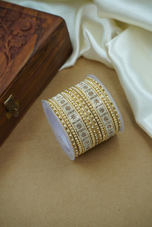Roll of gold bangles on a beige surface with a wooden box in the background by hitesh bangles