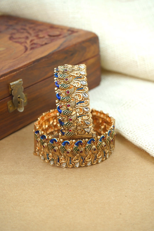 Decorative gold bangles with gemstones on a beige surface by hitesh bangles