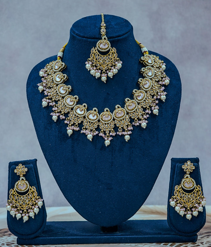 Gold and pearl jewelry set on a blue stand with a gray background by hitesh bangles