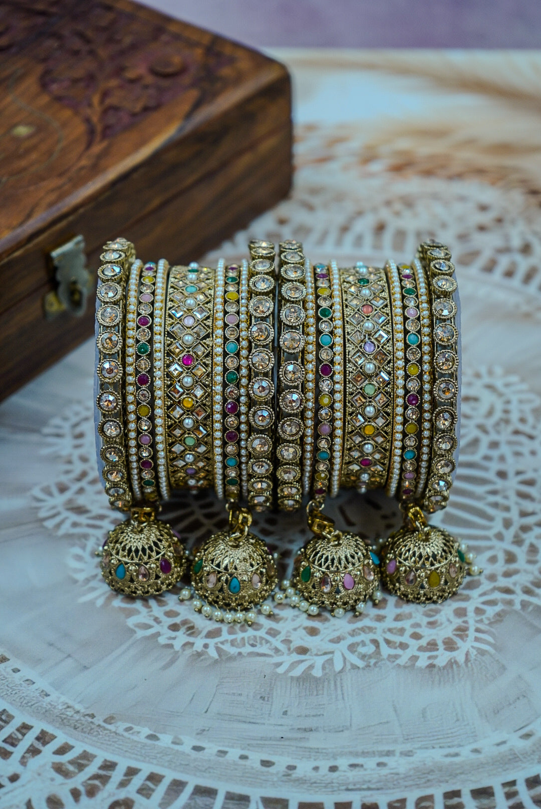 Set of ornate bangles with colorful stones on a textured surface by hitesh bangles