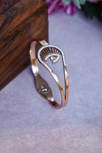 Rose gold bracelet with a decorative design on a gray surface by hitesh bangles