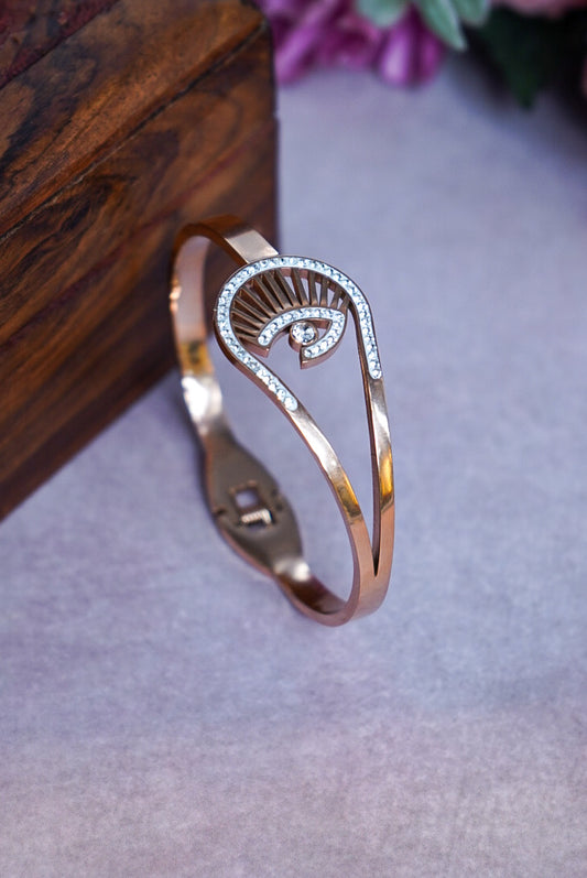 Rose gold bracelet with a decorative design on a gray surface by hitesh bangles