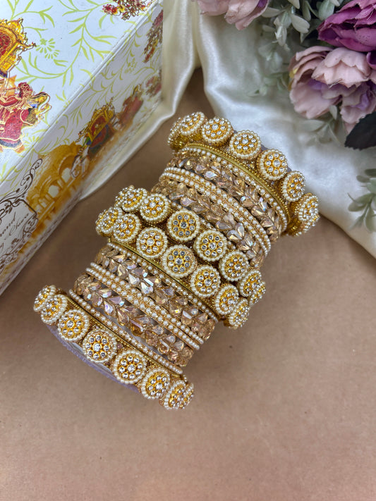 Decorative gold bangles on a beige surface with a floral background by hitesh bangles