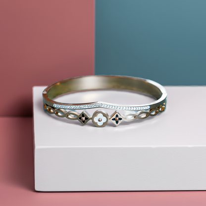 Silver bracelet with floral designs on a white box against a pink and blue background by hitesh bangles