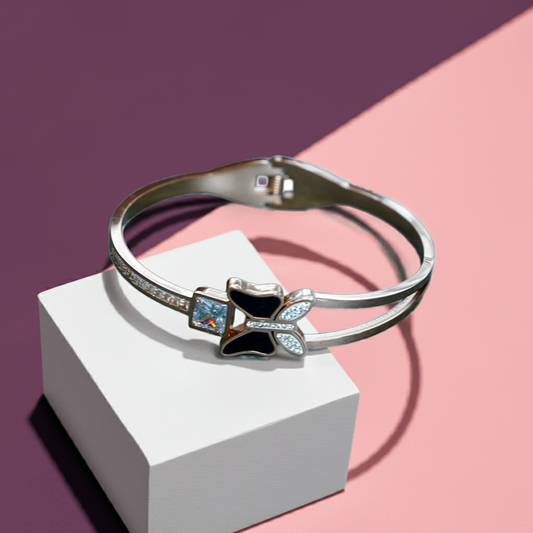 Silver bracelet with gemstones on a white block against a pink and purple background by hitesh bangles