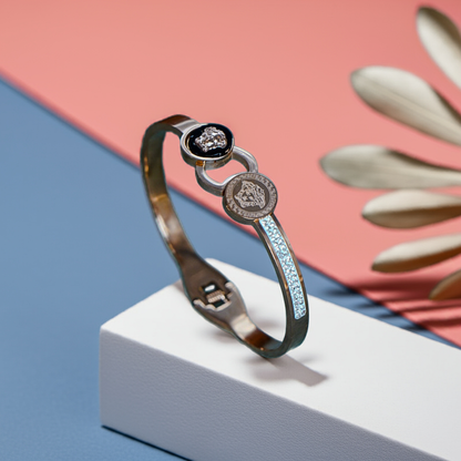 Silver bracelet with gemstones on a white block against a pink and blue background by hitesh bangles