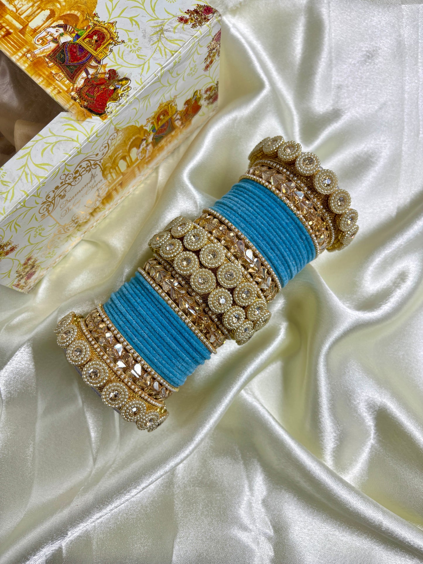Decorative blue and gold bangles on a white satin surface by hitesh bangles