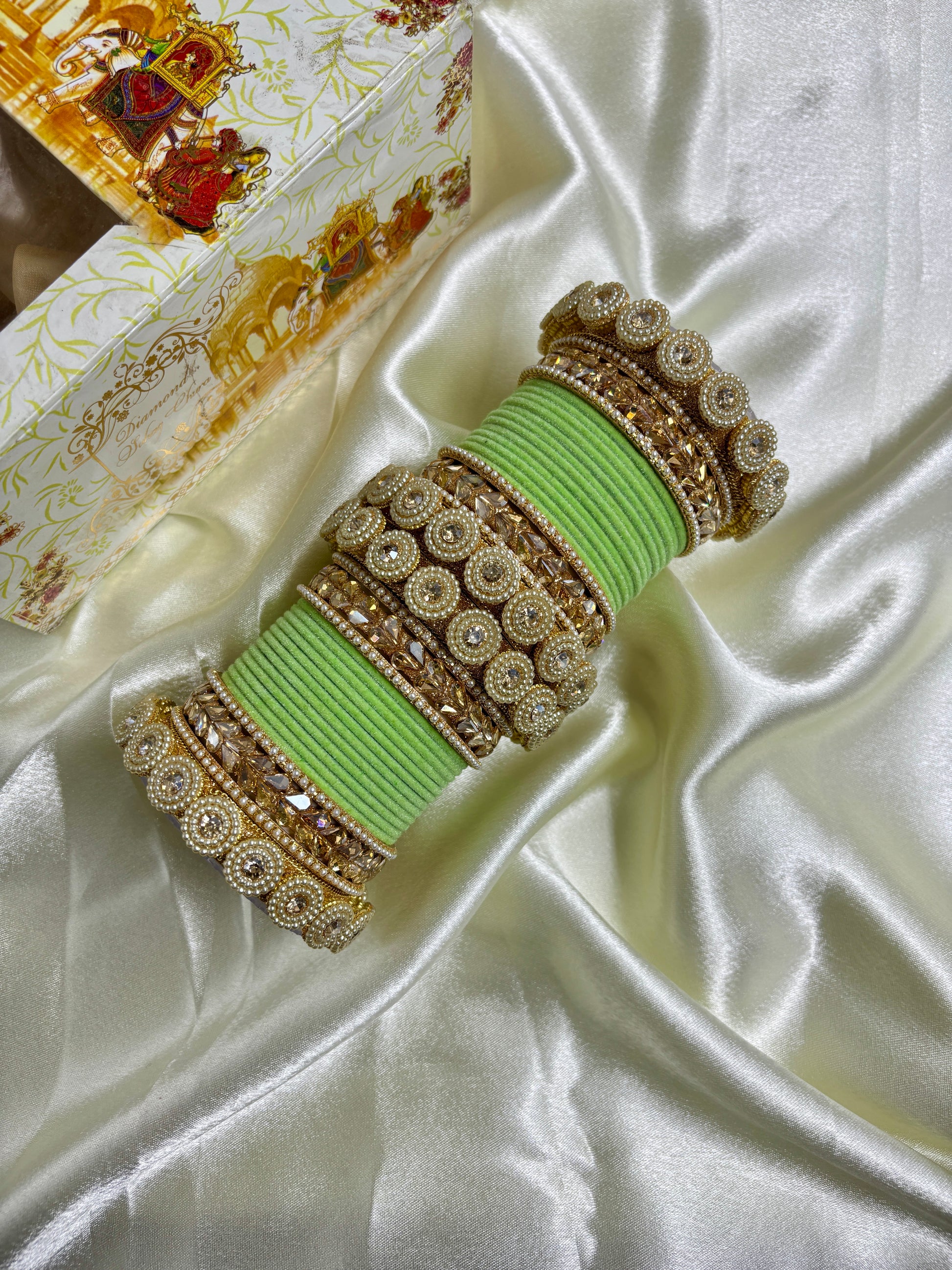 Decorative green and gold bracelet on a satin surface by hitesh bangles