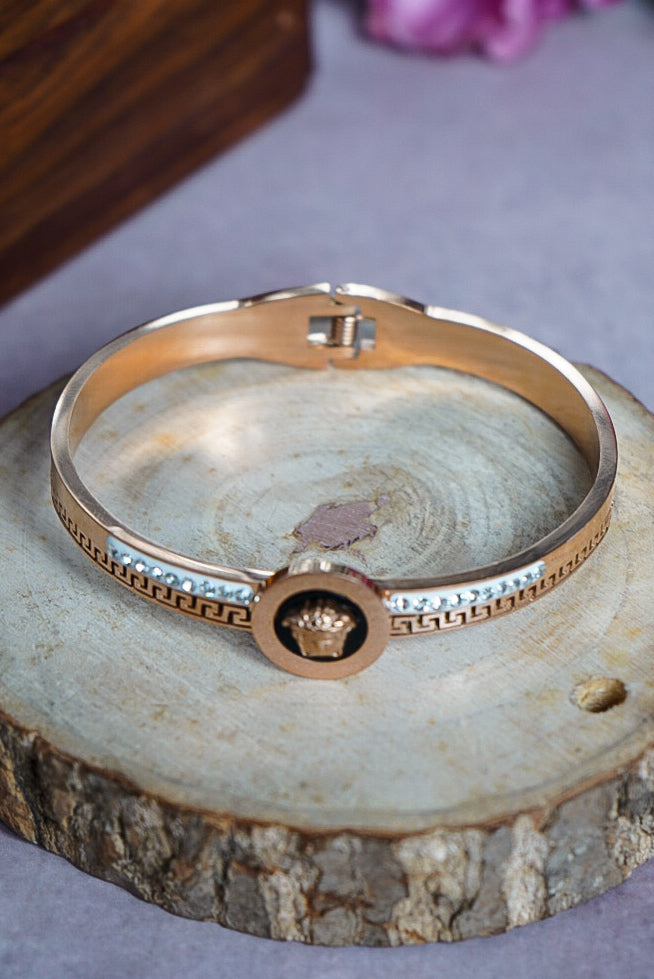 Gold bracelet with a brand logo on a wooden surface by hitesh bangles