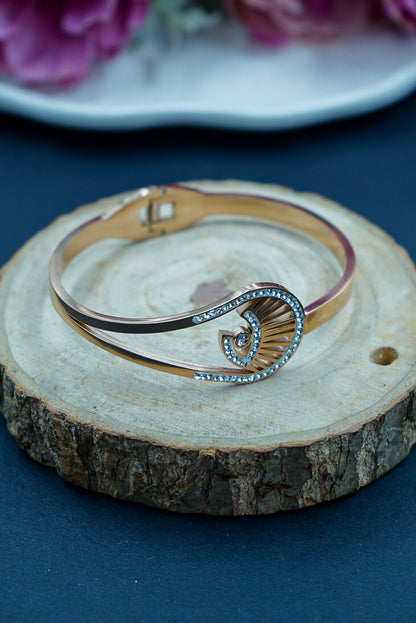 Gold and silver bracelet on a wooden surface with flowers in the background by hitesh bangles