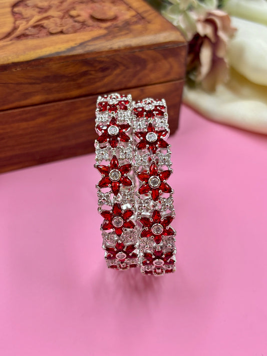 Red and silver floral bracelet on a pink surface with a wooden box in the background by hiesh bangles