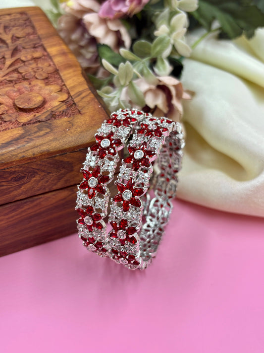 Decorative ring with red gemstones on a pink surface with floral and wooden background by hitesh bangles