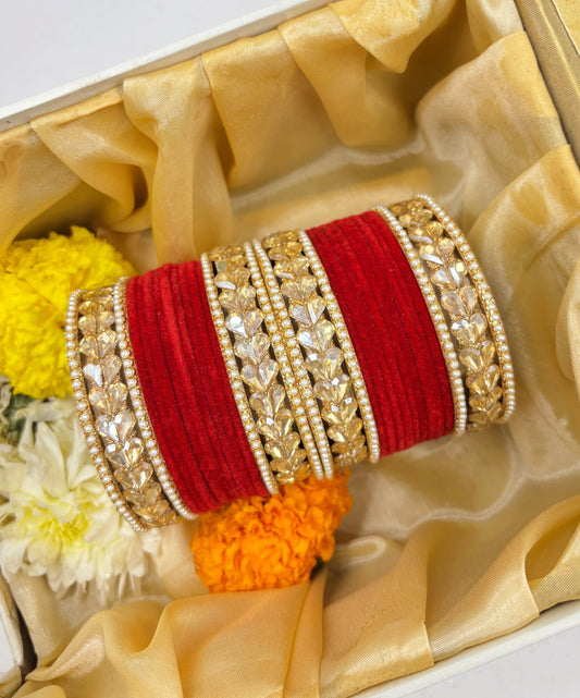 Decorative bangles with red and gold design on a beige fabric background by hitesh bangles