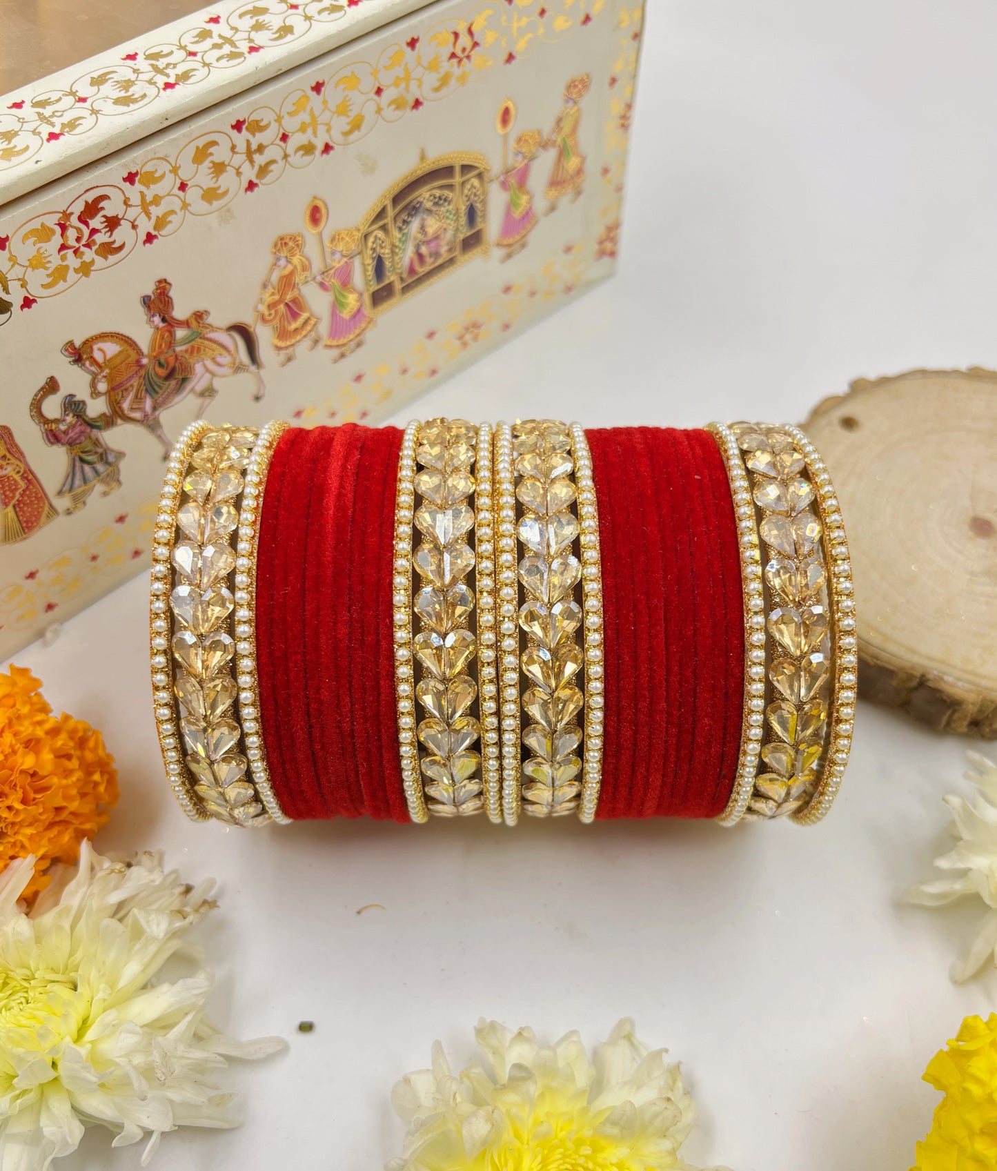 Decorative red and gold bangles with a decorative box in the background by hitesh bangles