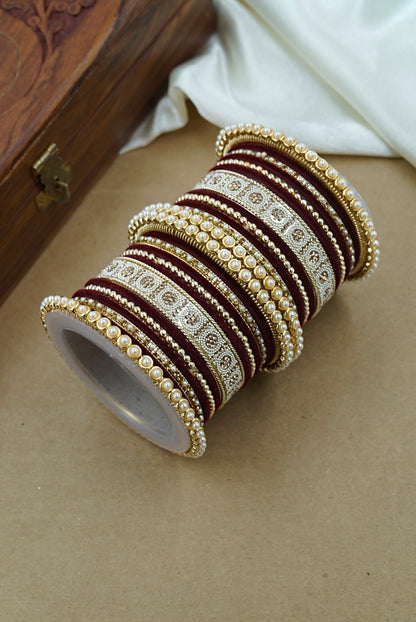 Set of decorative bangles on a beige surface with a wooden box in the background by hitesh bangles