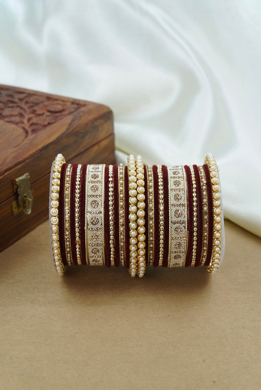 Set of decorative bangles with intricate designs on a beige surface by hitesh bangles