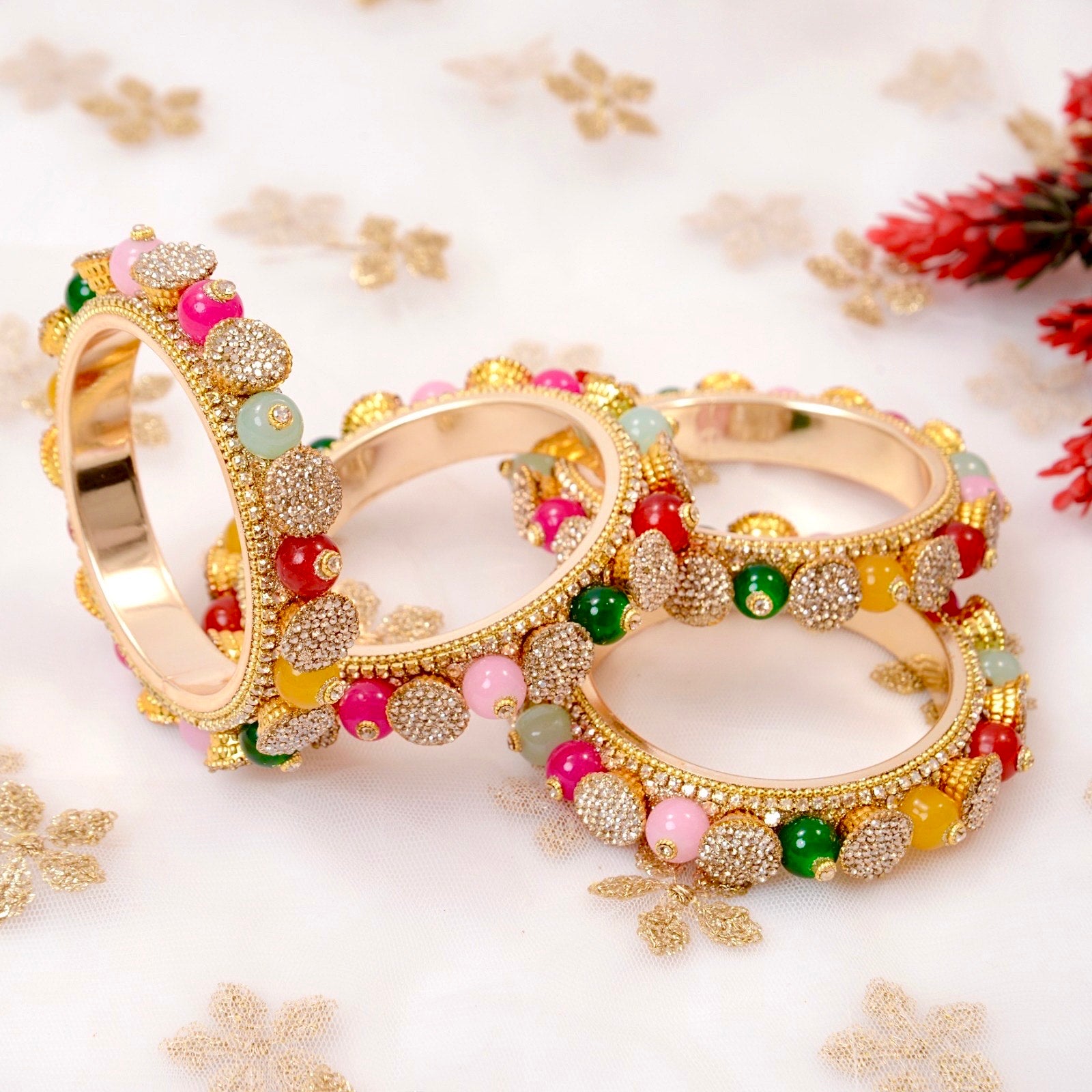 Pair of gold bangles with colorful beads on a decorative background by hitesh bangles