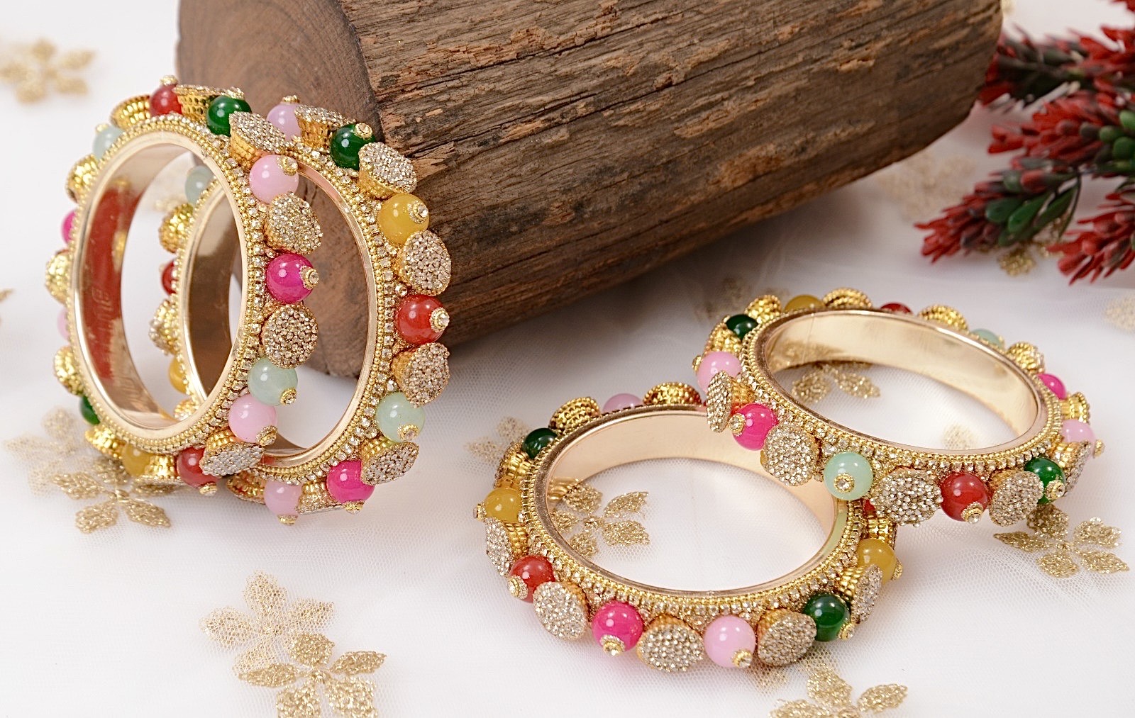 Gold bangles with colorful beads on a wooden surface by hitesh bangles