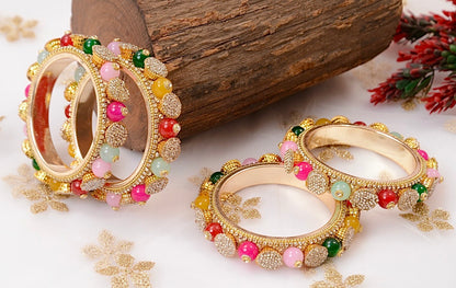 Gold bangles with colorful beads on a wooden surface by hitesh bangles