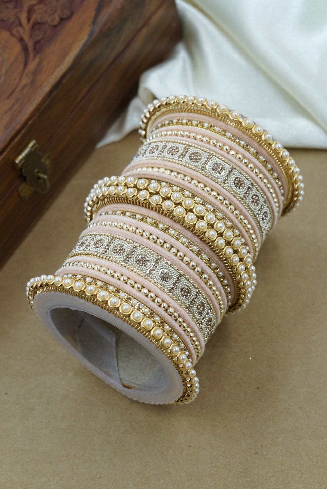 Set of decorative bangles on a textured surface with a wooden box in the background by hitesh bangles