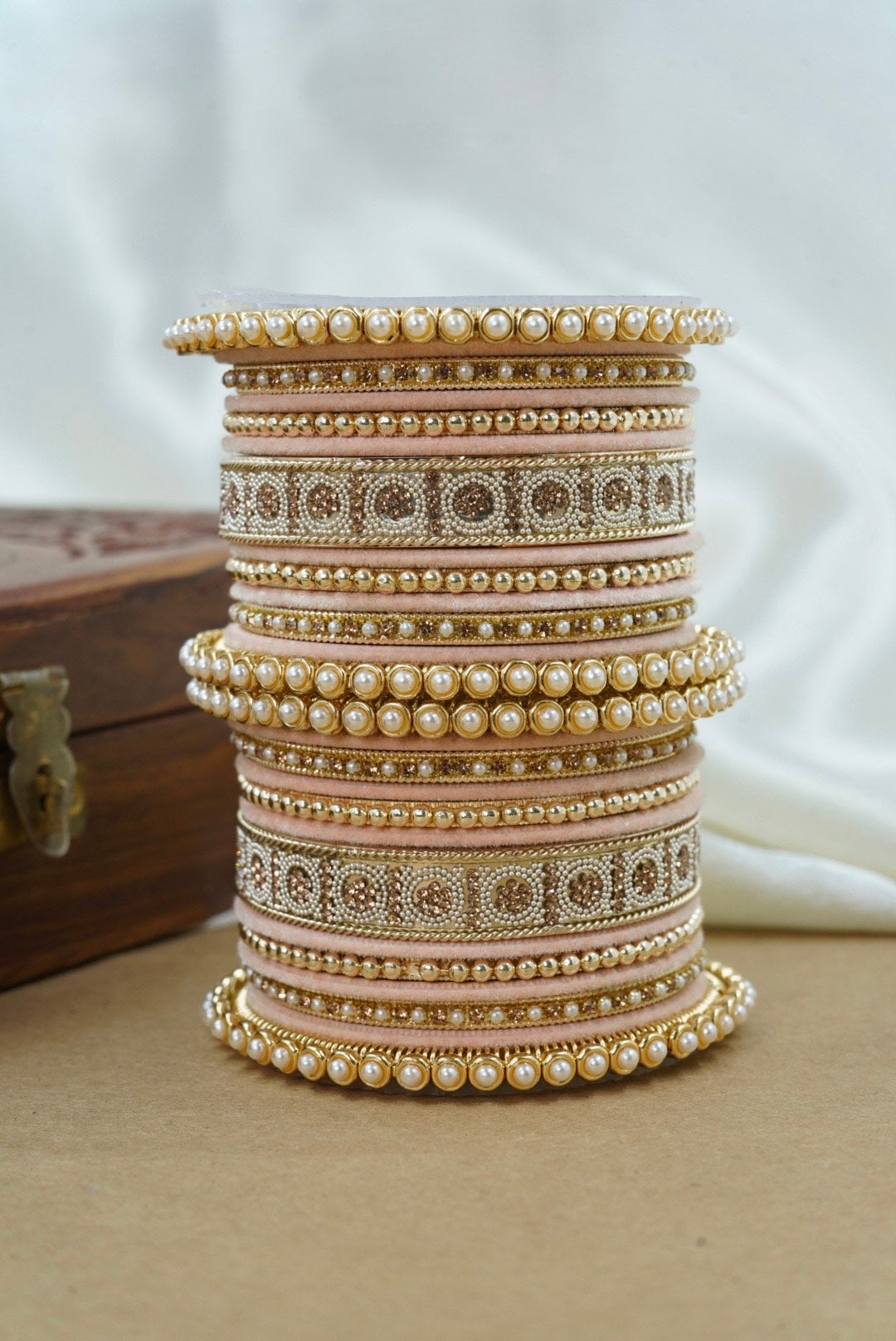 Stack of decorative bangles with intricate designs on a neutral background by hitesh bangles