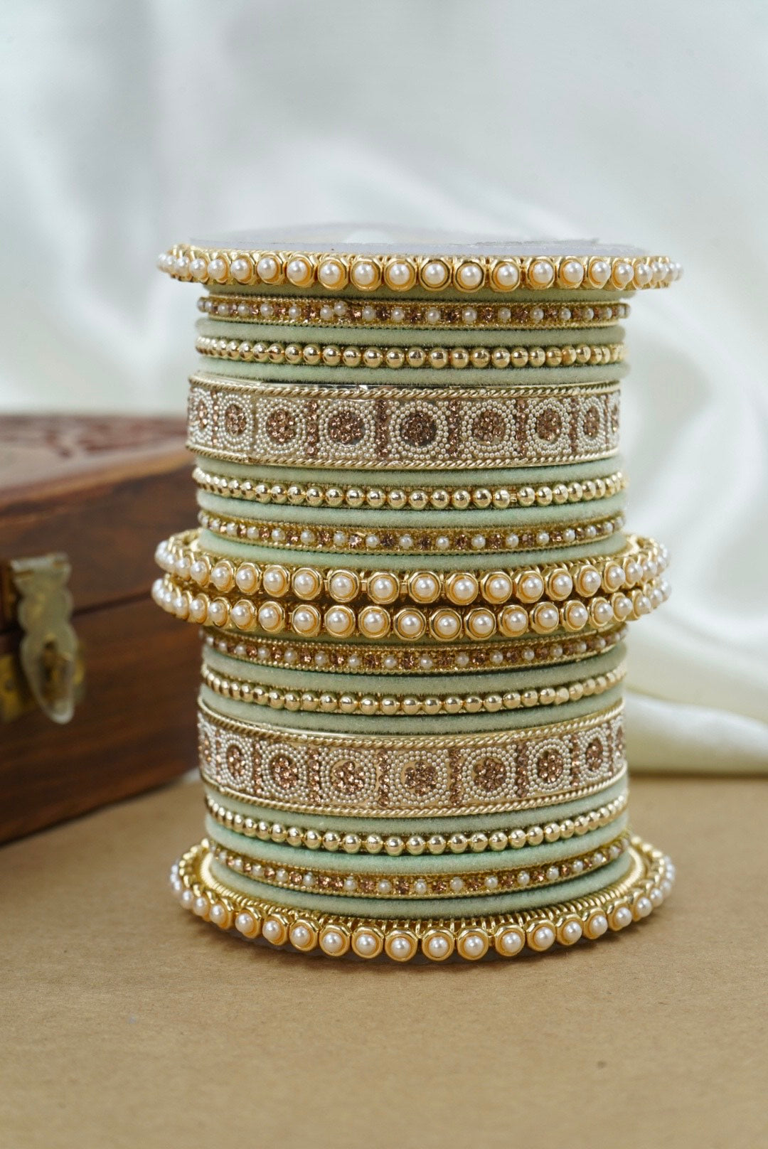 Stack of pearl and decorative bangles on a neutral background by hitesh bangles