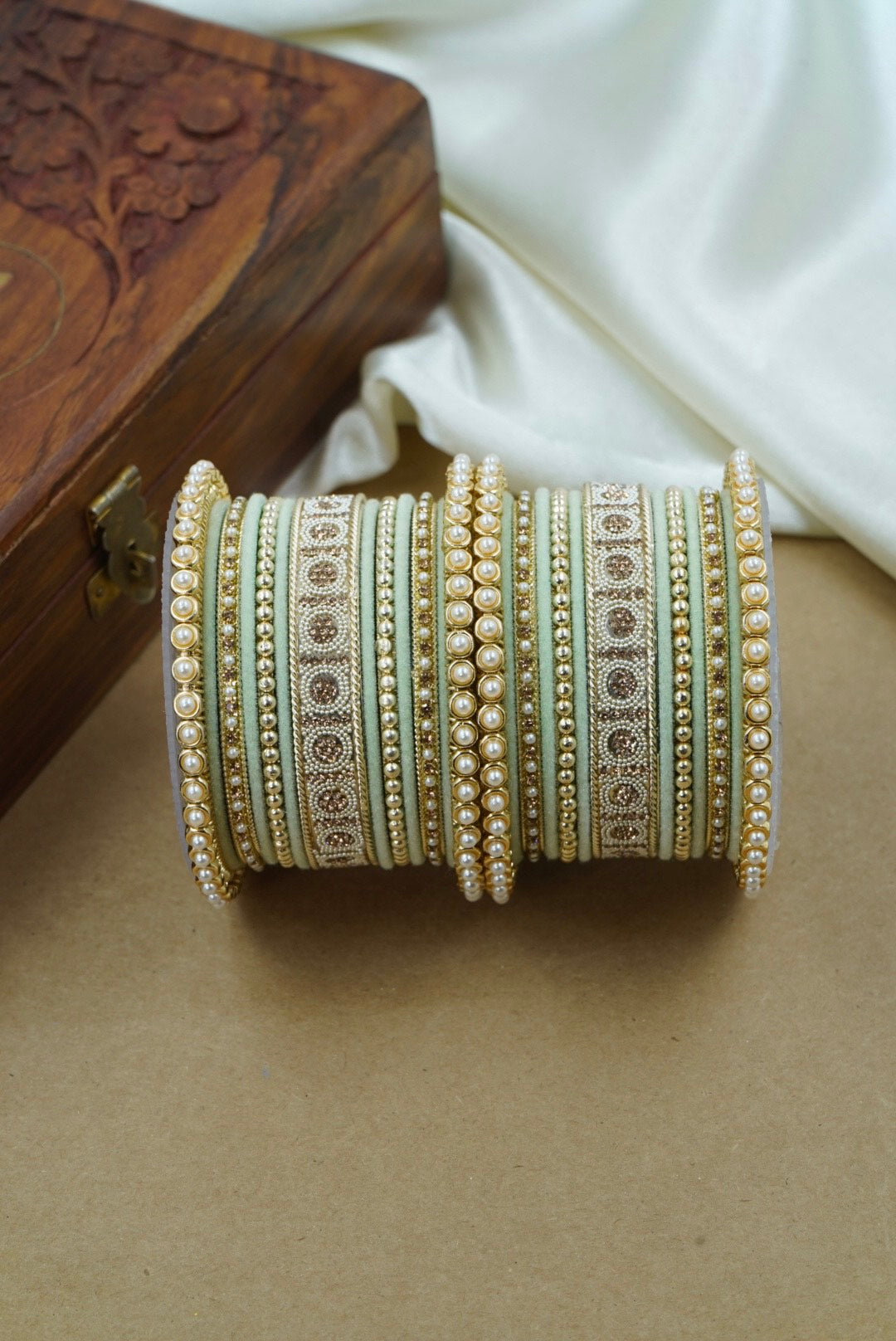 Decorative bangles on a beige surface with a wooden box in the background by hitesh bangles