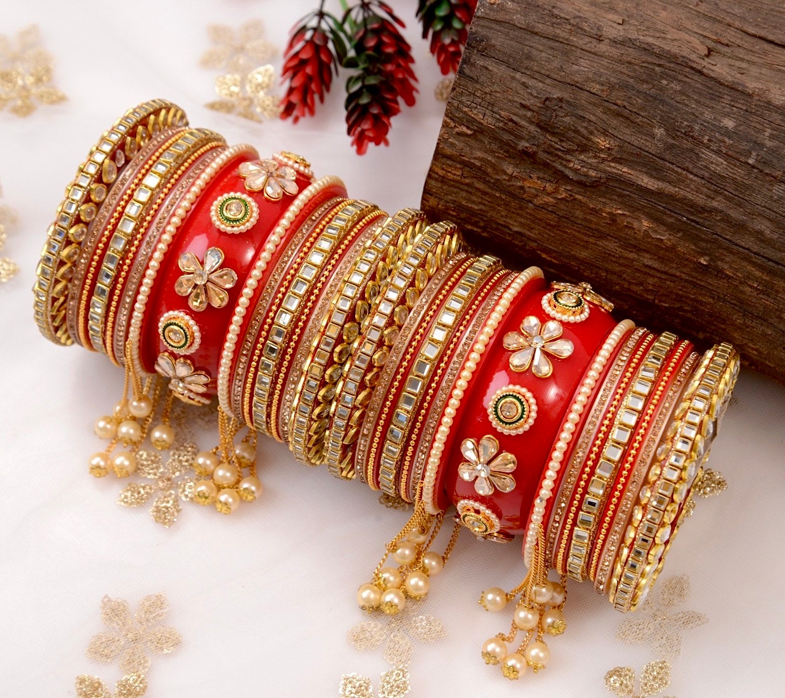 Decorative red and gold bangles with floral patterns on a white background by hitesh bangles
