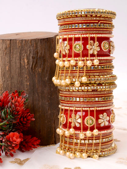 Stack of ornate bangles on a red cylindrical stand with floral decorations by hitesh bangles