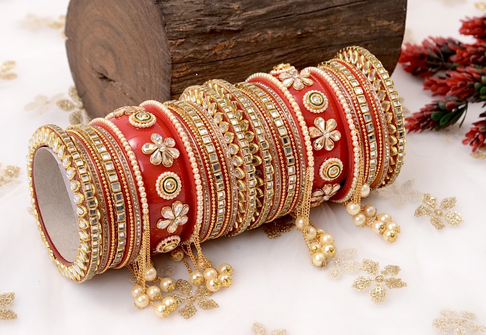 Red and gold bangles with floral patterns on a white surface with decorative elements by hitesh bangles