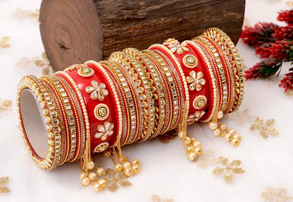 Red and gold bangles with floral patterns on a white surface with decorative elements by hitesh bangles