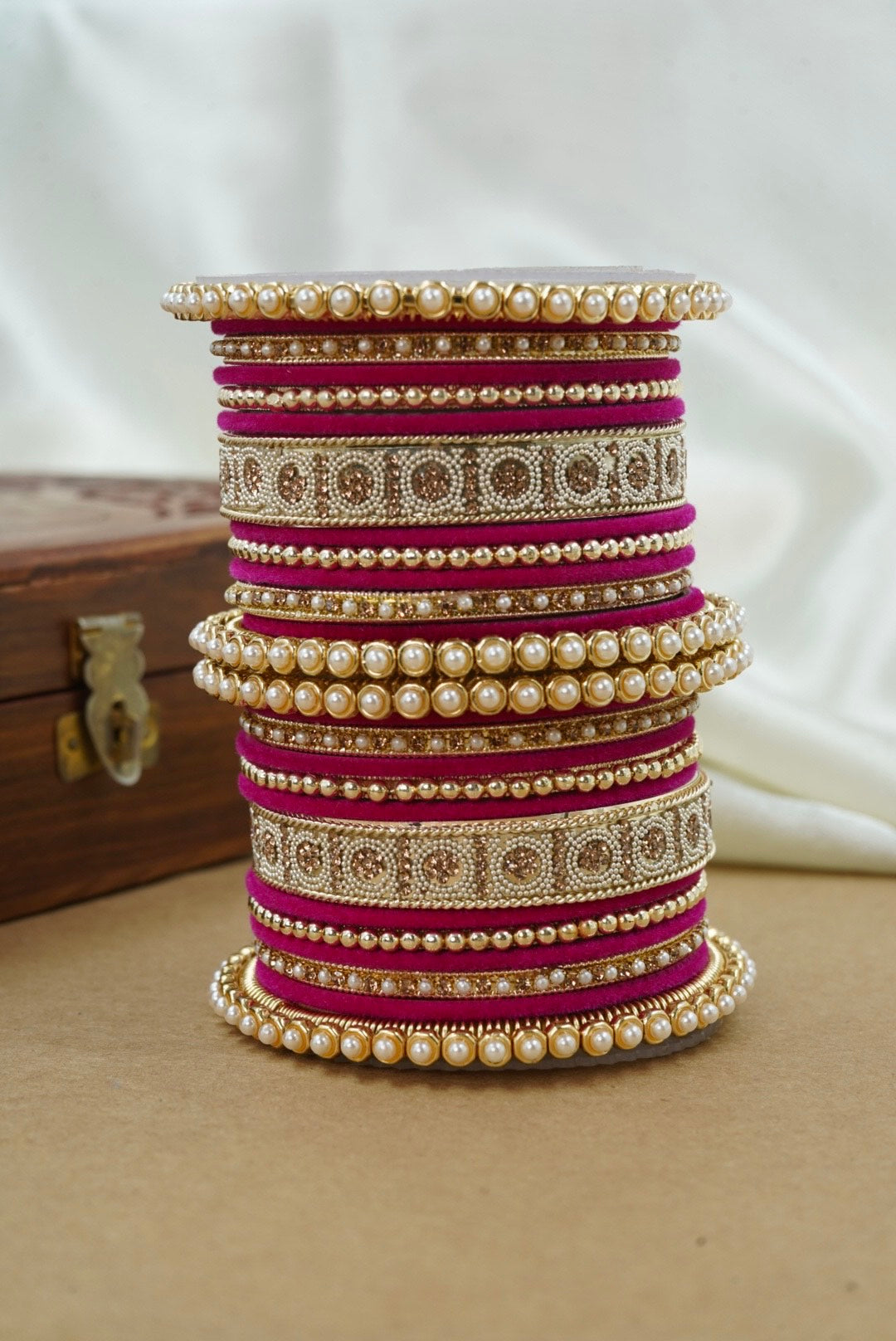 Stack of colorful bangles on a wooden surface with a white background by hitesh bangles