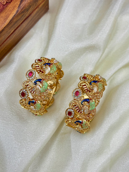 Gold earrings with colorful gemstones on a white fabric background by hitesh bangles
