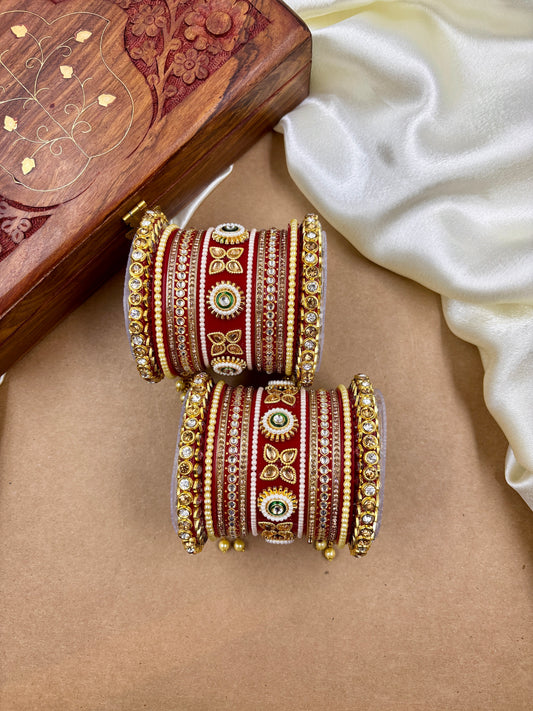 Decorative bangles with gold and red patterns on a beige surface with a wooden box in the background by hitesh bangles