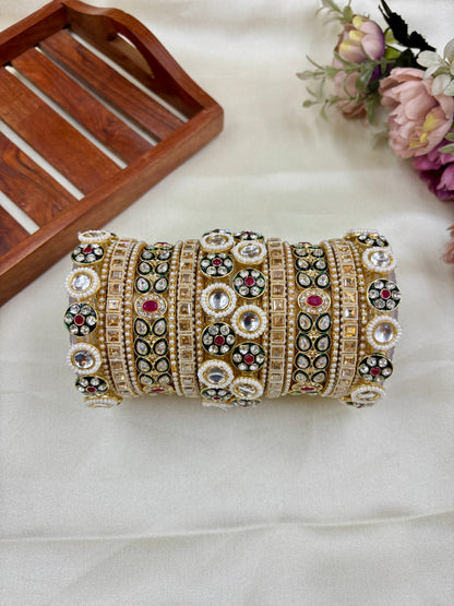 Decorative bangles with intricate designs on a white surface with a wooden tray and flowers in the background by hitesh bangles